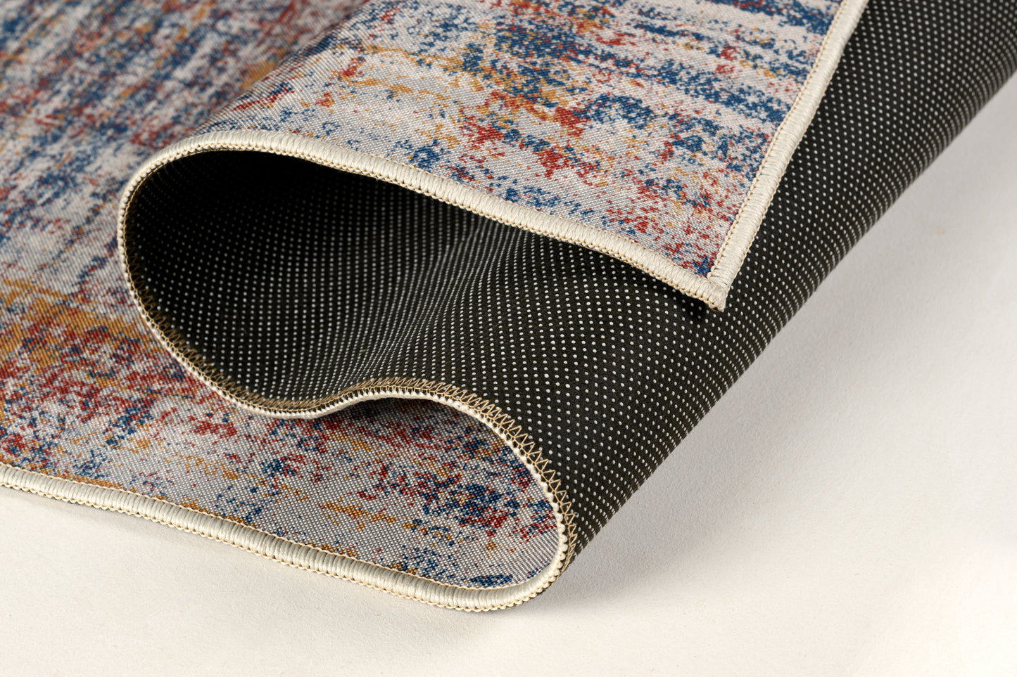 Close-up of a textured rug with a colorful pattern on a light background