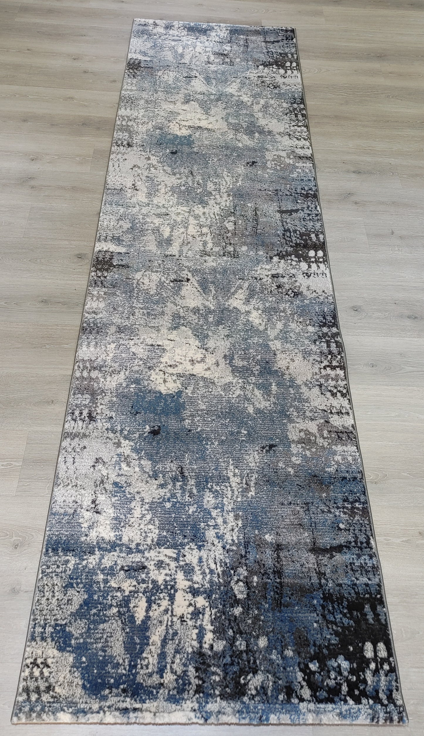 Long rectangular rug with abstract pattern on a wooden floor