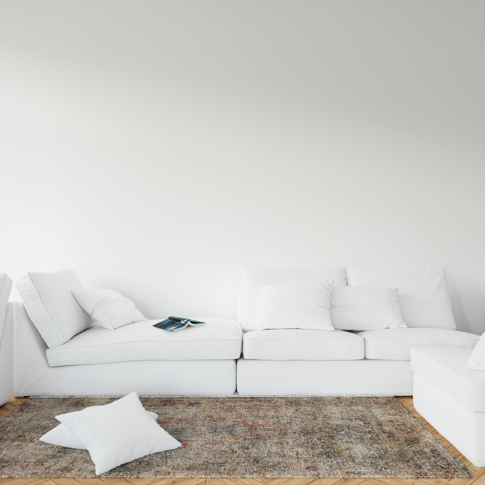 White sectional sofa with cushions on a textured rug against a white wall