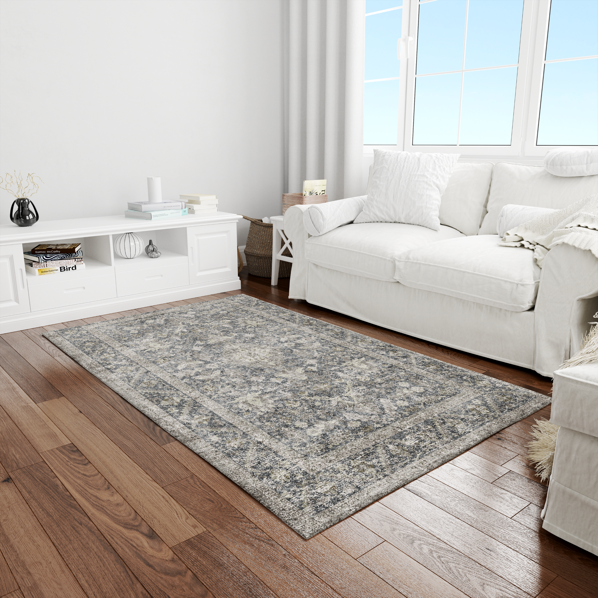 Living room with a gray area rug, white sofa, and wooden floor.
