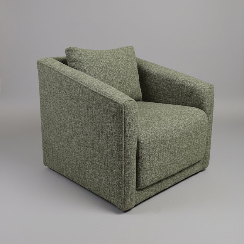 Green upholstered chair in a room with a door and plant in the background