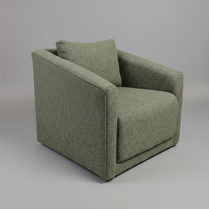 Green upholstered chair in a room with a door and plant in the background