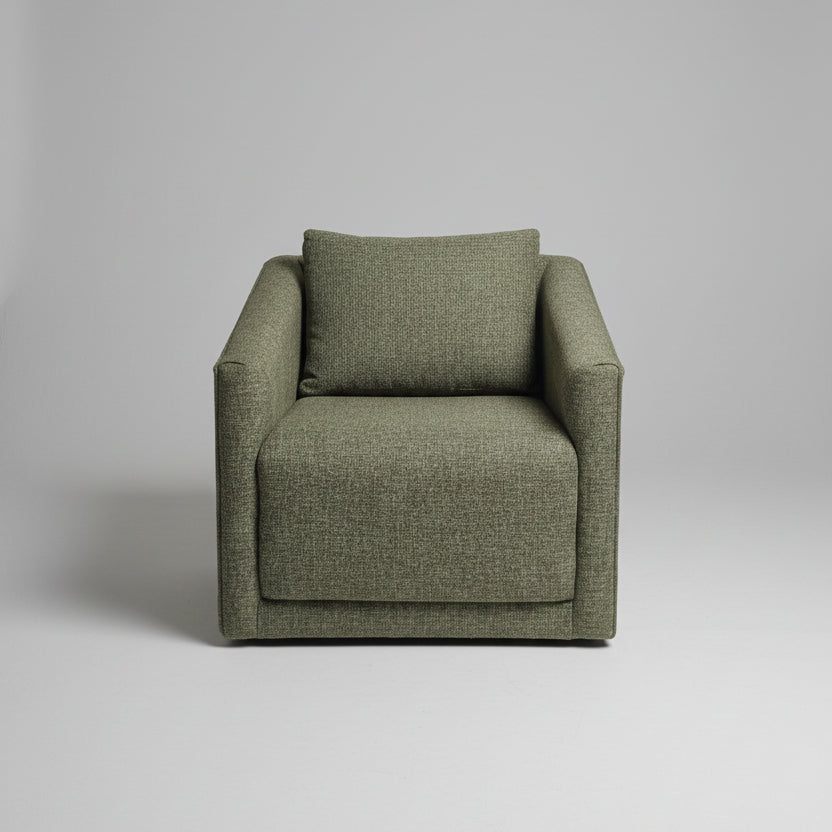 Green armchair in a room with shelves and various items.