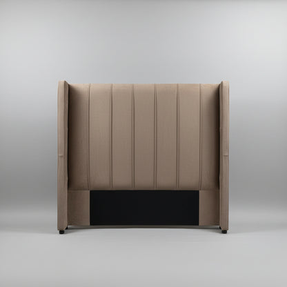 A tall upholstered headboard with vertical channel tufting and wingback sides, shown standing against a light gray wall on a tiled floor.