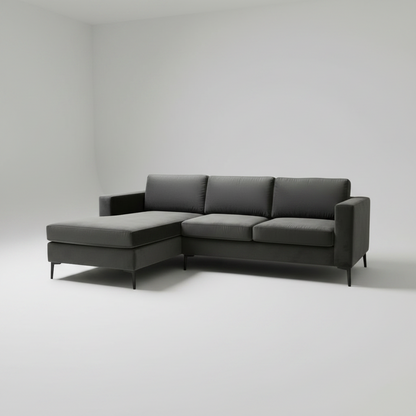 A modern dark gray L-shaped sectional sofa with a chaise lounge on the left side, shown in a minimalist studio setting with a light gray background.