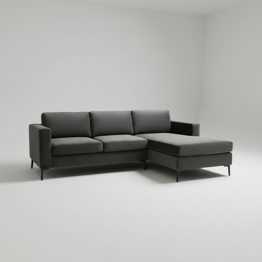 A modern dark gray sectional sofa with a right-facing chaise lounge, shown in a minimalist studio setting with a light gray background.