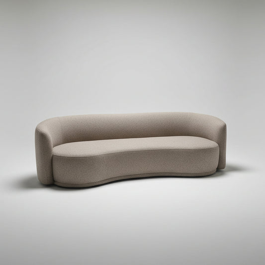 A curved, low-profile upholstered sofa in a textured taupe-beige fabric, photographed in a furniture showroom with other sofas and a concrete floor visible.