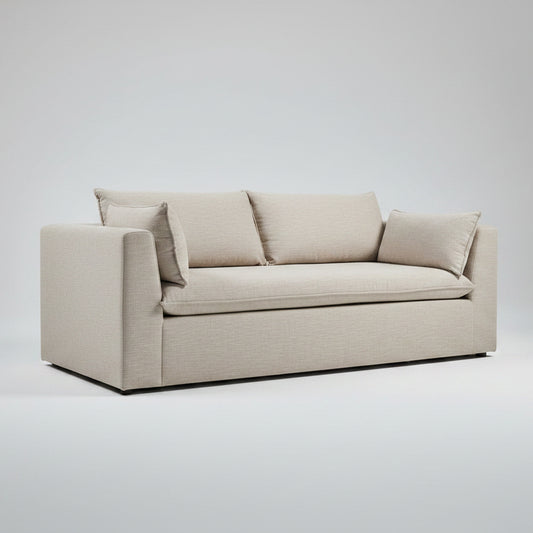 A light beige upholstered loveseat sofa with two matching throw pillows, positioned in a warehouse showroom setting.