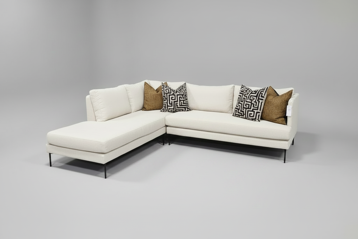 White sectional sofa with patterned pillows on a gray background
