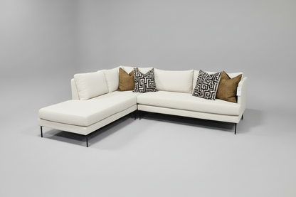 White sectional sofa with patterned pillows on a gray background
