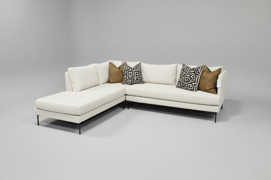 White sectional sofa with patterned pillows on a gray background