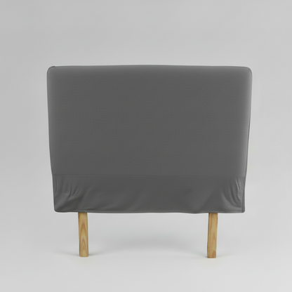 Gray upholstered slip cover headboard with wooden legs on a light grey background