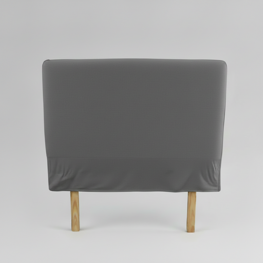 Gray upholstered slip cover headboard with wooden legs on a light grey background