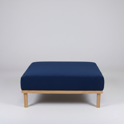 Navy blue ottoman with wooden legs on a light gray background