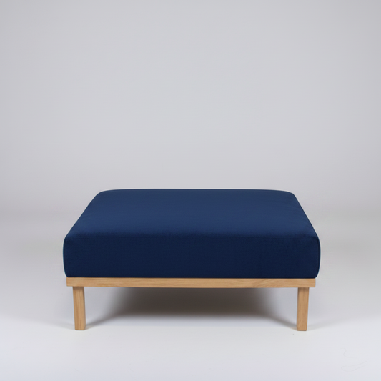 Navy blue ottoman with wooden legs on a light gray background