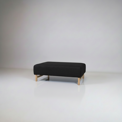 Black ottoman with wooden legs on a white background