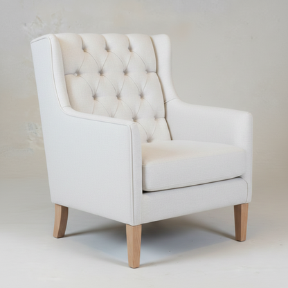 White upholstered armchair with tufted backrest on a plain background