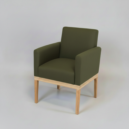 Green armchair with wooden legs on a light gray background