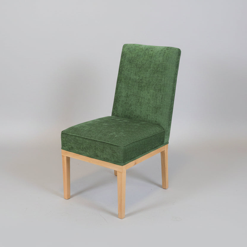 Green upholstered chair on a white tiled floor with a plain white wall background