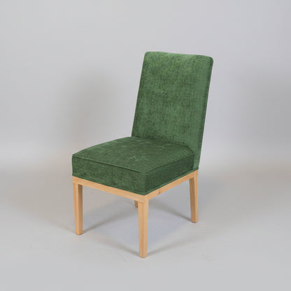 Green upholstered chair on a white tiled floor with a plain white wall background