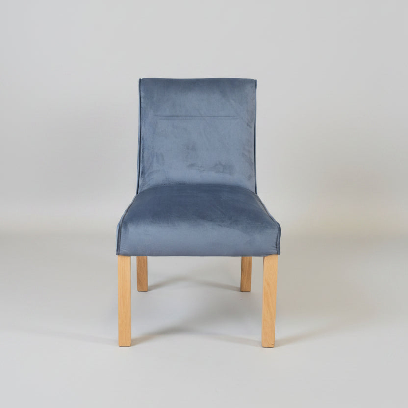 Gray upholstered chair with wooden legs on a tiled floor and light gray wall background