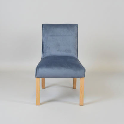 Gray upholstered chair with wooden legs on a tiled floor and light gray wall background
