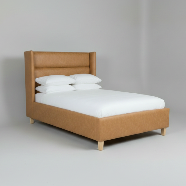 Brown upholstered bed with white mattress and pillows on a gray background