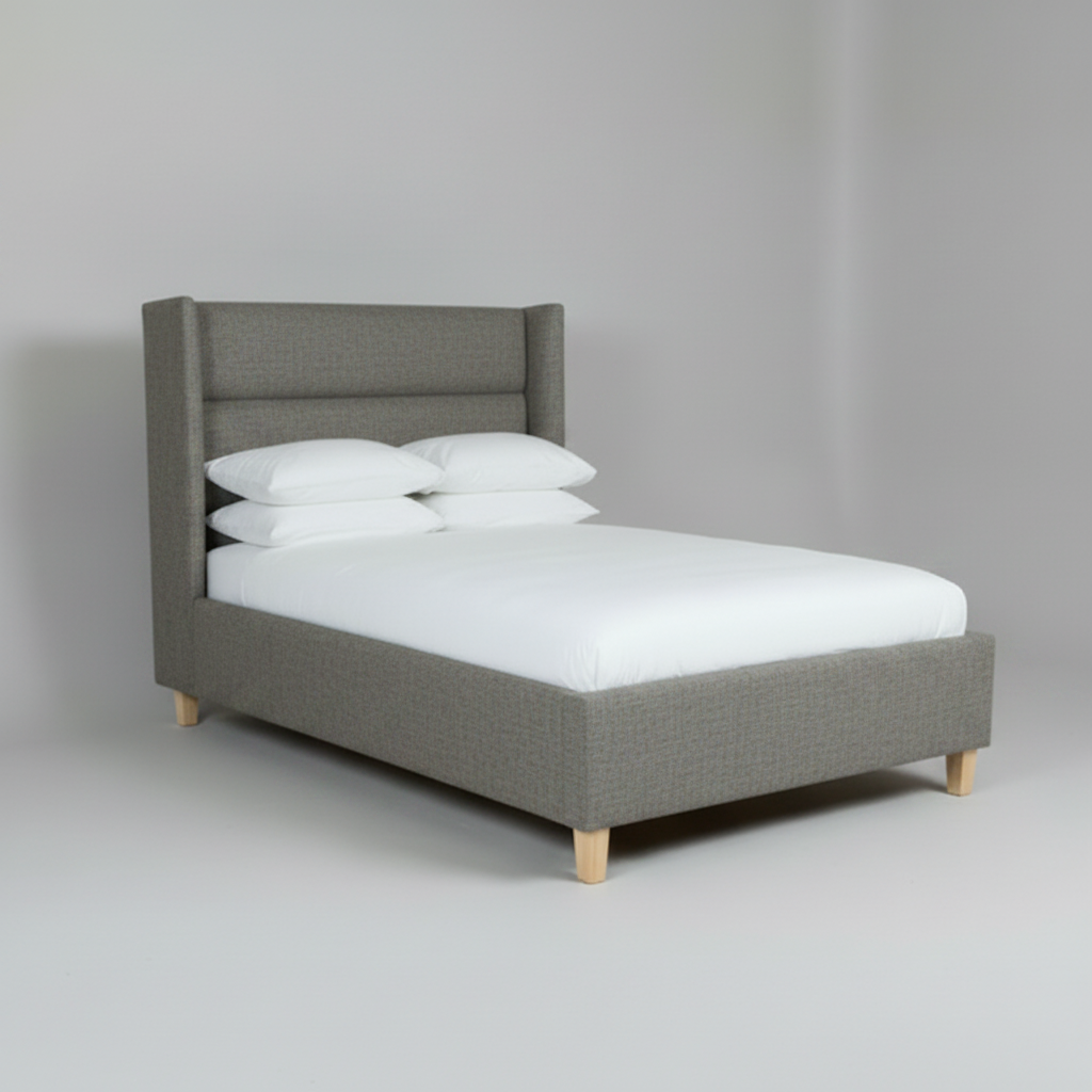 Gray upholstered bed with white bedding on a plain background