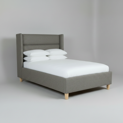 Gray upholstered bed with white bedding on a plain background