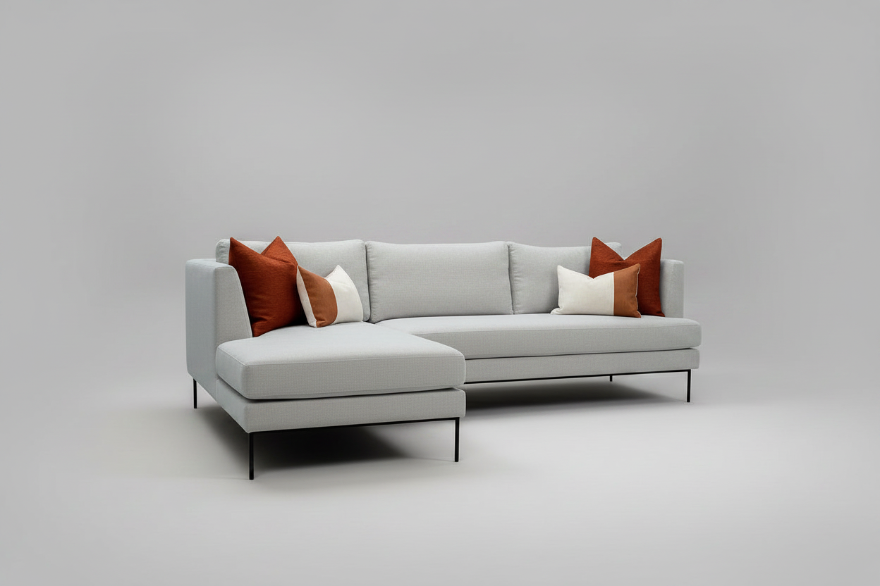 Gray sectional sofa with orange and white pillows on a gray background