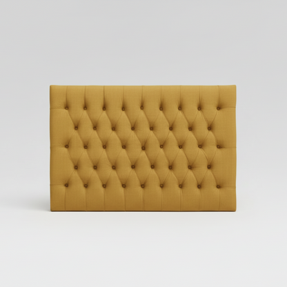 Mustard yellow tufted headboard on a white background