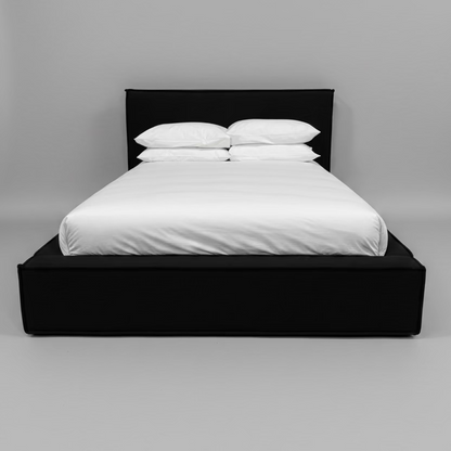 Black bed frame with white bedding against a beige wall.