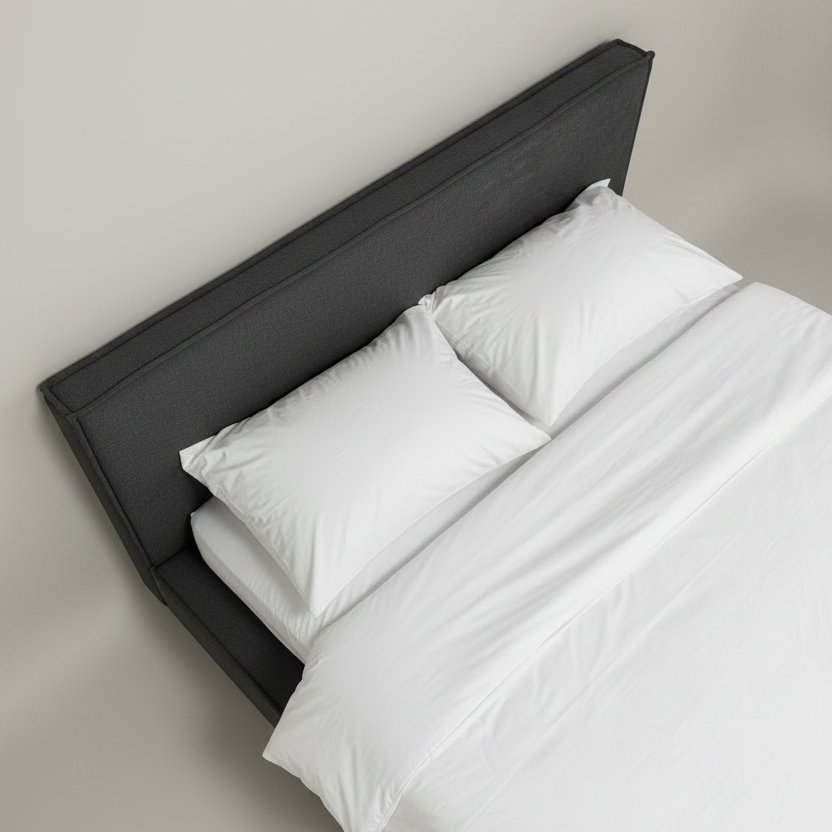 Bed with white bedding and a dark headboard against a plain wall