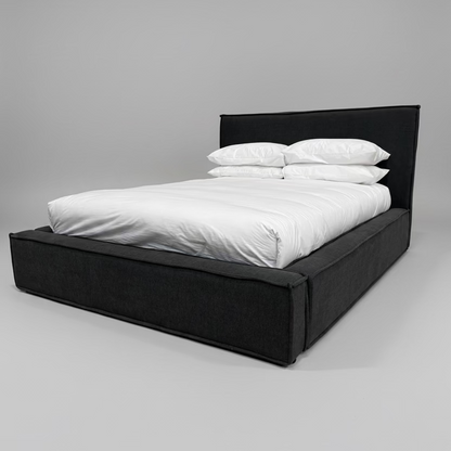 Black bed frame with white bedding against a gray wall.