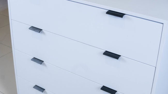 Sleek Chest of Drawers in white melamine with black handles.